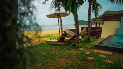 a house with a pool and a chair and an umbrella at Baan SanSuk Pranburi - Beach Front & Pool Villa in Pran Buri