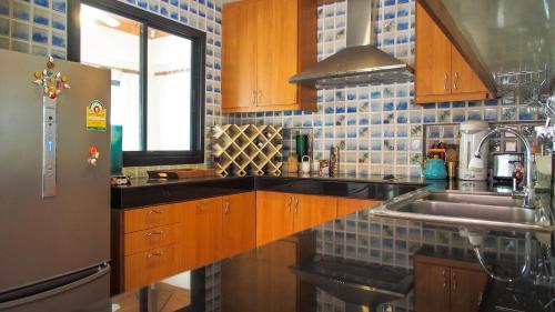 a kitchen with wooden cabinets and a sink at Baan SanSuk Pranburi - Beach Front & Pool Villa in Pran Buri