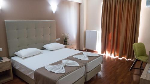 a bedroom with a white bed and a green chair at Kornilios Palace in Anchialos