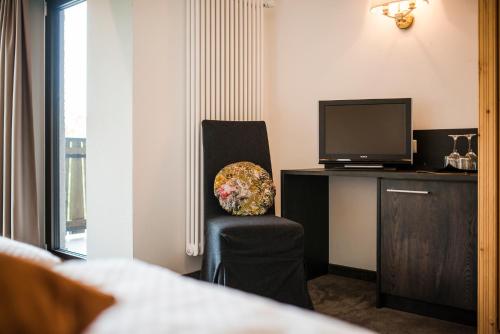 a hotel room with a chair and a television at Hotel Restaurant Kirchsteiger in Vollan