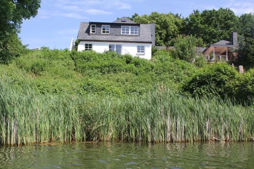 a house on top of a hill next to a body of water at Ferienhaus direkt am Schmalensee in Schmalensee