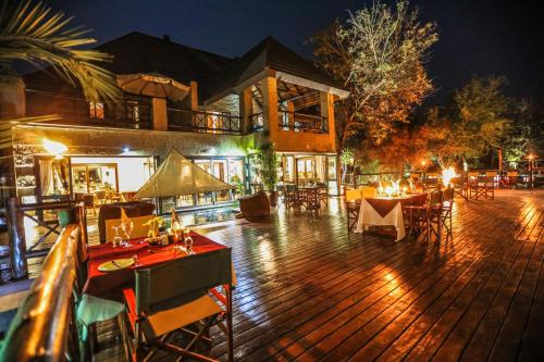 an outdoor deck with tables and chairs at night at Grand Kruger Lodge and Spa in Marloth Park