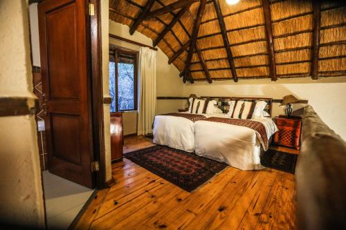 a bedroom with a bed and a wooden floor at Grand Kruger Lodge and Spa in Marloth Park
