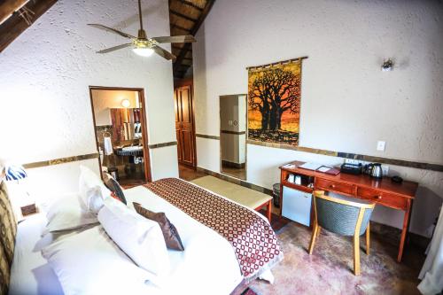 a bedroom with a desk and a bed and a desk sidx sidx sidx at Grand Kruger Lodge and Spa in Marloth Park