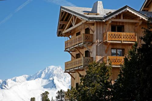 a wooden building with balconies and snow covered mountains at Travelski Home Premium - Résidence Chalets Altitude & Ours 5 stars in Arc 2000