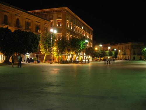 una piazza di città di notte con un grande edificio di Casa di Azzurra a Sciacca