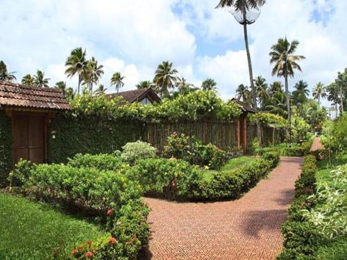 a garden with a brick walkway in front of a house at Abad Whispering Palms in Kumarakom