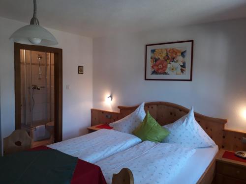 a bedroom with a bed with white sheets and colorful pillows at Haus Morgensonne in Pettneu am Arlberg