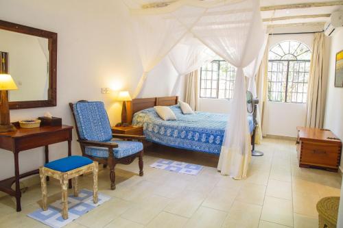 1 dormitorio con cama, silla y escritorio en Mwanana House, en Watamu