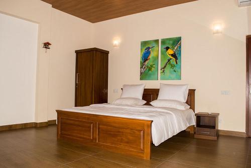 a bedroom with a bed with two paintings on the wall at Gurubeula Leisure As You Wish in Deniyaya