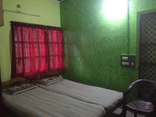 a bed in a room with a green wall at Nimmu Guest House & Restaurant Gokarna in Gokarna