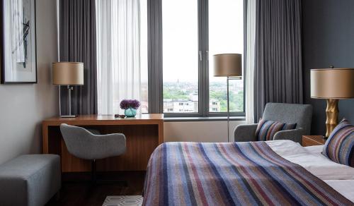 ケルンにあるAMERON Köln Hotel Regentのベッド、デスク、窓が備わるホテルルームです。