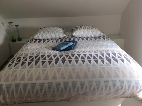 a bed with white comforter and a blue object on it at Biotina in Lebbeke