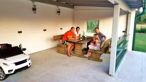 a group of people sitting at a table in a garage with a car at Haus Floresa in Lutzmannsburg