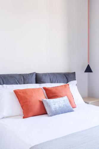 a white bed with orange and gray pillows on it at Gianburrasca in Florence