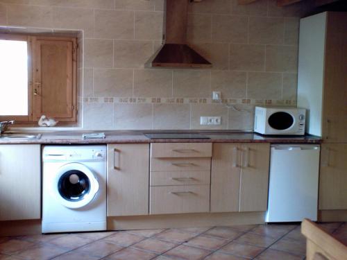 uma cozinha com uma máquina de lavar roupa e um micro-ondas em Casa para vacaciones junto al Parque de la Naturaleza de Cabarceno em Obregón