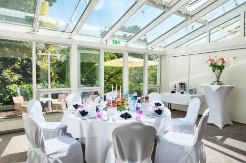 a room with white tables and chairs and windows at ACHAT Hotel Bad Dürkheim in Bad Dürkheim