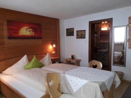 a bedroom with a white bed with a table and chairs at Haus Morgensonne in Pettneu am Arlberg