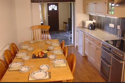 uma cozinha com uma mesa de madeira com placas em Coach House Cottage em Merton