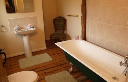 a bathroom with a tub and a sink and a toilet at Coach House Cottage in Merton