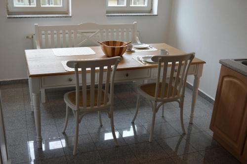 Stadt Apartment Nr. 1 Bad Wilsnack في باد فيلسناك: طاولة مطبخ مع كرسيين ومكتب مع وعاء عليه