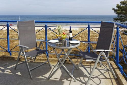 d'une table et de deux chaises sur un balcon donnant sur la plage. dans l'établissement Haus auf der Duene Fewo Ostseeblick, à Trassenheide