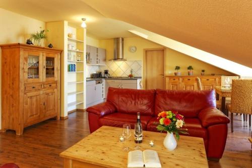 - un salon avec un canapé en cuir rouge et une table dans l'établissement Haus auf der Duene Fewo Ostseeblick, à Trassenheide
