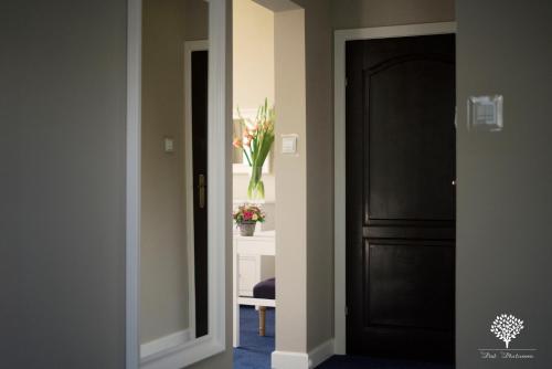 a hallway with a black door and a vase of flowers at Szafirowy Dwór Hotel & Restauracja in Gliwice