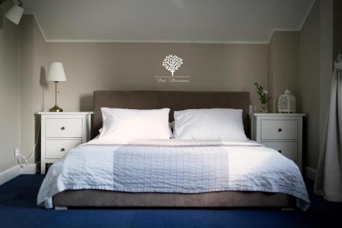 a bedroom with a bed with white sheets and two night stands at Szafirowy Dwór Hotel & Restauracja in Gliwice