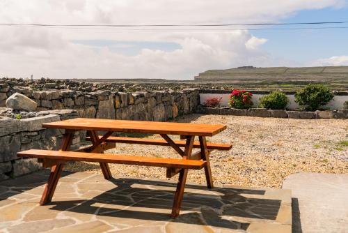 a wooden bench sitting on top of a stone wall at Aran Walkers Lodge in Inis Mor