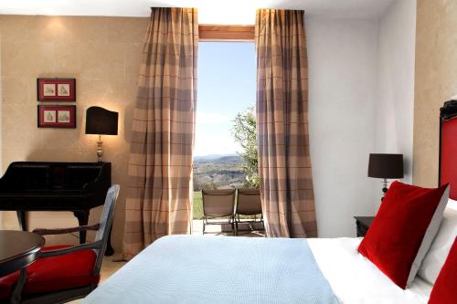a bedroom with a bed and a desk and a window at Castello di Velona Resort, Thermal SPA & Winery in Montalcino