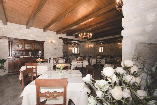 un restaurante con mesas blancas, sillas y flores en Il Vecchio Frantoio, en Grottaminarda