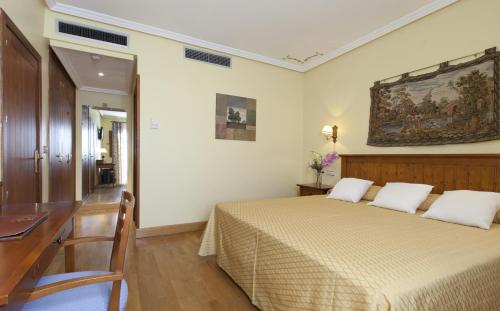 um quarto com uma cama com uma secretária e um quadro na parede em Hotel Casona de la Reyna em Toledo