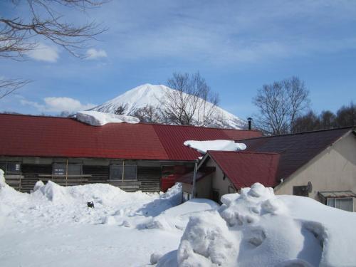 a snow covered house with a snow covered mountain in the background at Boken Kazoku in Kutchan