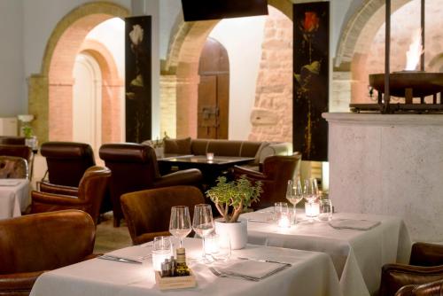 a restaurant with tables and chairs with white tablecloths at Castello di Velona Resort, Thermal SPA & Winery in Montalcino