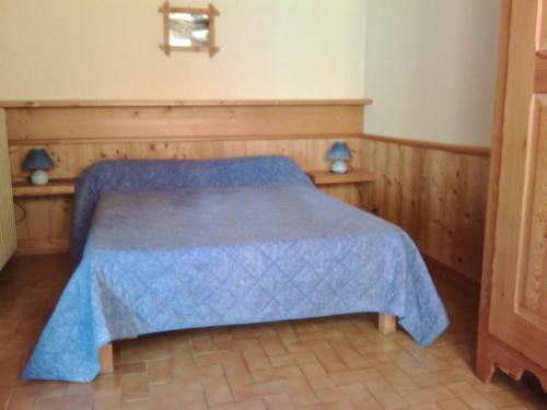 een slaapkamer met een bed met een blauwe sprei bij les fenêtres du mont blanc in La Giettaz