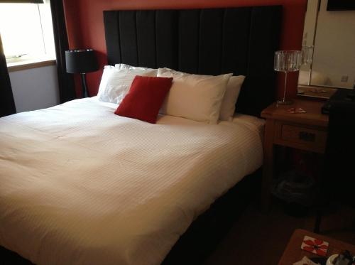 a bedroom with a white bed with a red pillow at The Neuk in Portlethen