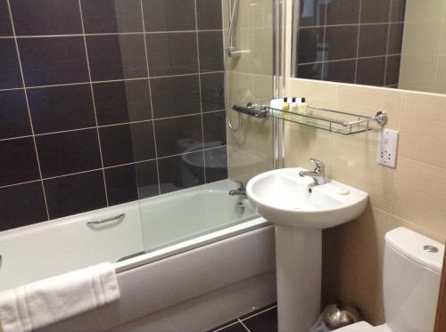 a bathroom with a sink and a toilet and a bath tub at The Neuk in Portlethen