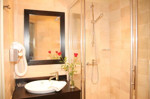 a bathroom with a shower, sink, and mirror at La Place Boutique Hotel in Antibes