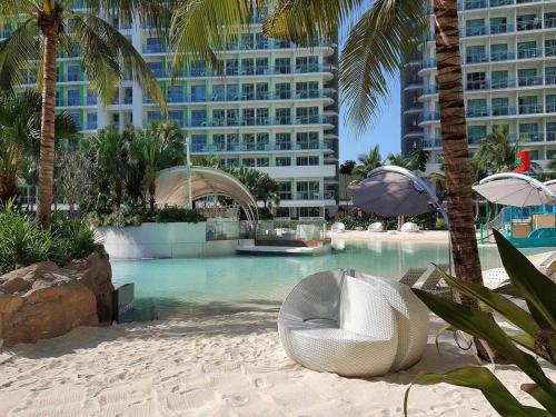 une piscine avec une chaise et des palmiers ainsi qu'un bâtiment dans l'établissement Azure Peaceful and Beachy Staycation, à Manille