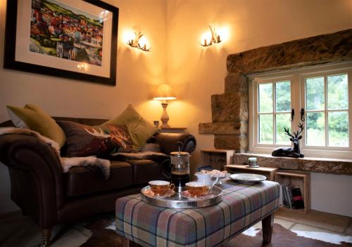 ein Wohnzimmer mit einem Sofa und einem Tisch in der Unterkunft Bluebells Cottage in Chop Gate