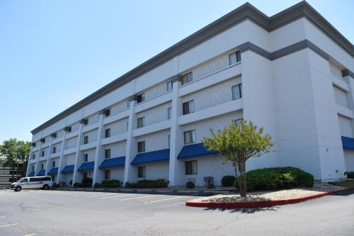 a large white building with a tree in a parking lot at Baymont by Wyndham Texarkana in Texarkana