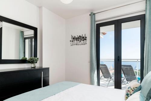 een slaapkamer met een bed en een spiegel en een balkon bij Caniço VI by An Island Apart in Santa Cruz