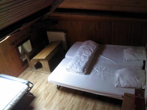 - une chambre avec un lit blanc et du parquet dans l'établissement Gîte communal, à Futeau