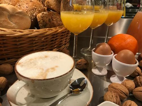 a table topped with a cup of coffee and glasses of orange juice at HHotel Augsburg in Augsburg