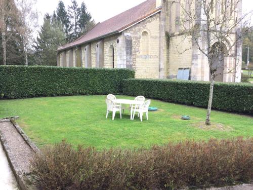two chairs and a table on a lawn in front of a building at Gîte communal in Futeau