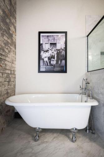 a white bath tub in a bathroom with a picture on the wall at GunRunner Boutique Hotel in Florence