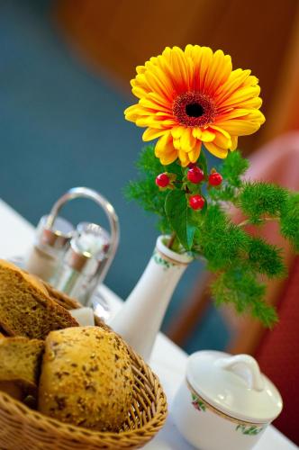 a vase with a yellow flower and a basket of bread at Gasthof Traube in San Lorenzo di Sebato