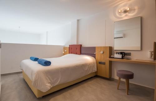 a bedroom with a bed and a desk and a mirror at Protaras Plaza Hotel in Protaras