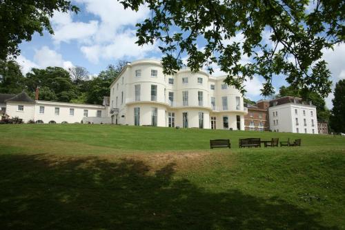 a large white house on a grassy field at Mercure Gloucester Bowden Hall Hotel in Gloucester